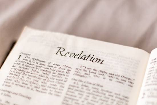 A Bible open to the first page of Revelation, which points to the final events before Christ's return.