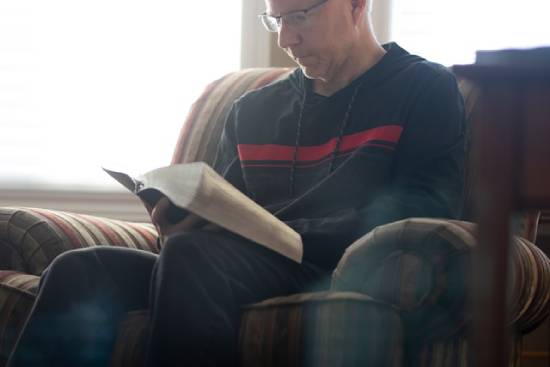 A man reads his Bible while sitting in an armchair. Even though the end times sound frightening, Jesus promises to lead His people through it all.