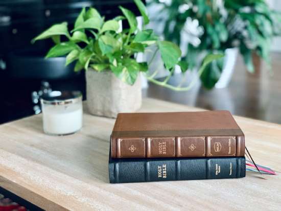 Two Bible versions on a desk A King James Version and New King James Version of the Bible resting on top of one another on a desk