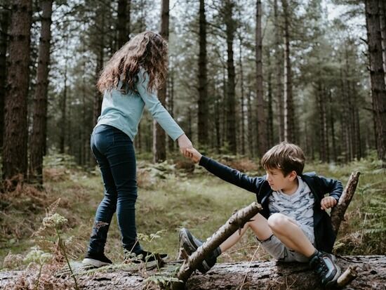 A sister showing unselfish love by giving her brother a hand after he fell