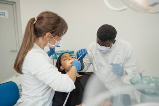  Two dentists clean a woman's teeth, illustrating how dentists can serve as medical missionaries, too.
