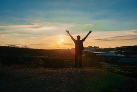 Silhouette of a Man Raising Hands at Sunset The image of a man raising his arms as He faces the setting sun shows that at the Second Coming, those who look forward to Jesus' return will be filled with joy and celebration.