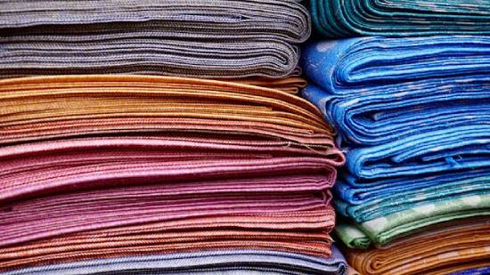 Two stacks of multiple pieces of colorful cloth neatly folded on top of one another.