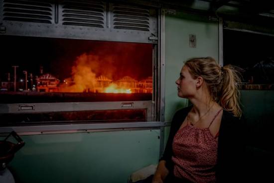 Woman Looking out Train Window at City Burning The image of a woman watching a fire blazing at houses across the street demonstrates the disasters on Earth that lead up to Christ's return. It reminds us to watch for Jesus, and that His return will be visible to all.