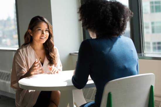 A woman sitting at a table with her boss, asking about Sabbath accommodations.