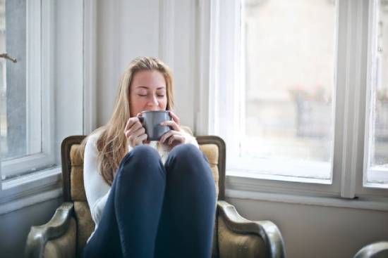 A woman resting on a chair, taking a sip of a relaxing cup of tea.