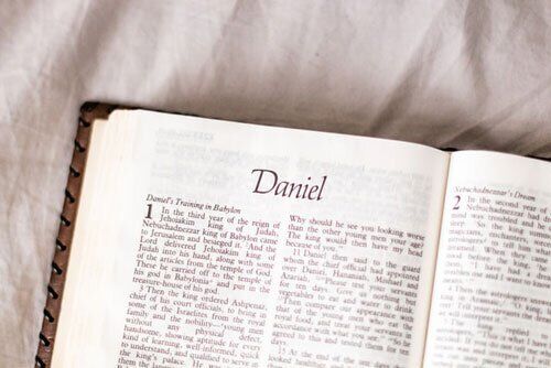 The Bible opened to Book of Daniel Biblical Book of the prophet Daniel as Adventist Evangelist delivers his sermon in an Evangelistic series on Bible prophecy