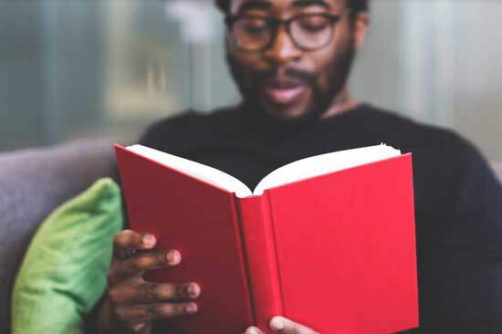 Reading Ellen White's book A man reading one of Ellen White's books with a red cover to test it for himself