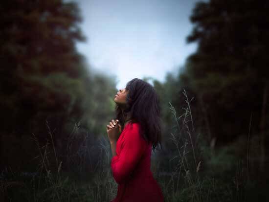 Woman in red praying Woman in red praying to Jesus, as He is with her through the presence of another Person of the Godhead, the Holy Spirit