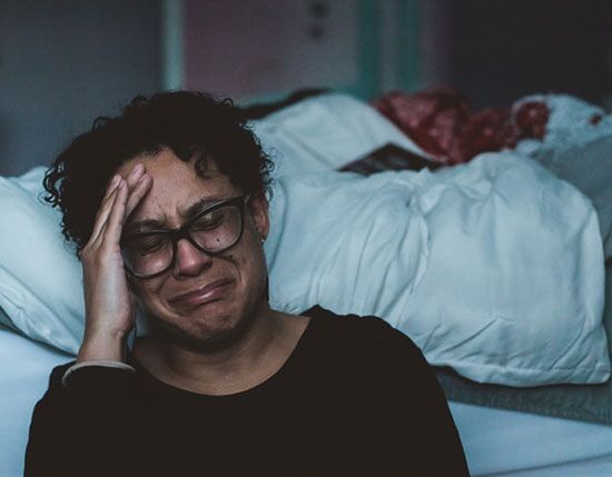 crying Woman grieving with hand up to face, eye closed, praying for help.