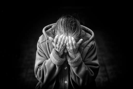 Woman with hands over her face grieving A woman leans forward with her hands covering her face. This is a common picture of when we think about grief.