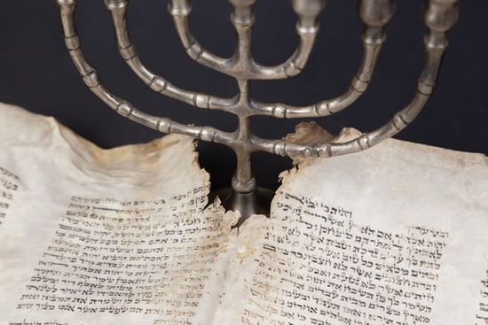 Candlestick and Scroll A seven-branched candlestick next to Hebrew scrolls of the Bible