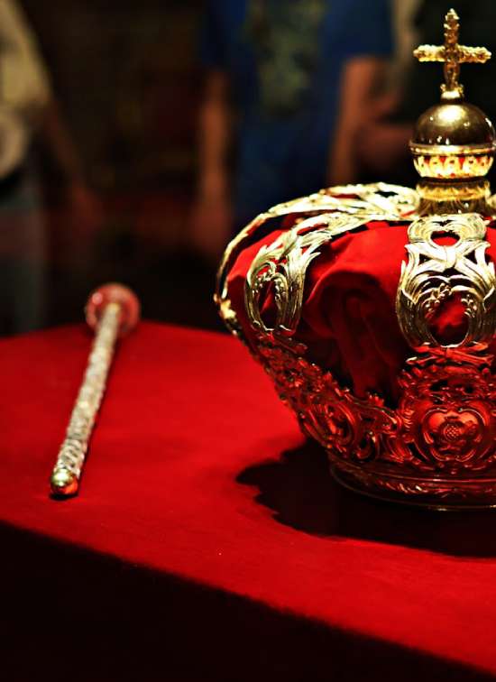 King's crown and scepter A royal crown and scepter resting on a red table.