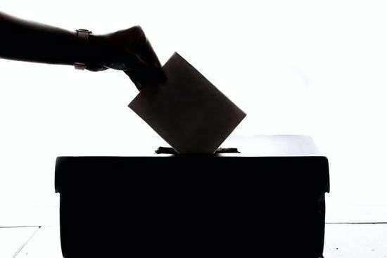 Voting ballot box A silhouette of a hand placing a written vote in a box