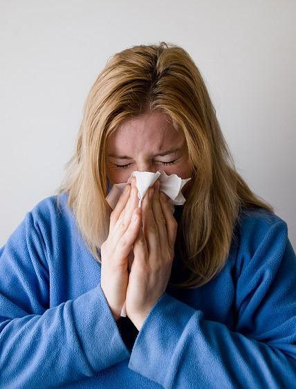 Woman blowing her nose A woman blowing her nose because her immune system is weakened from lack of sleep