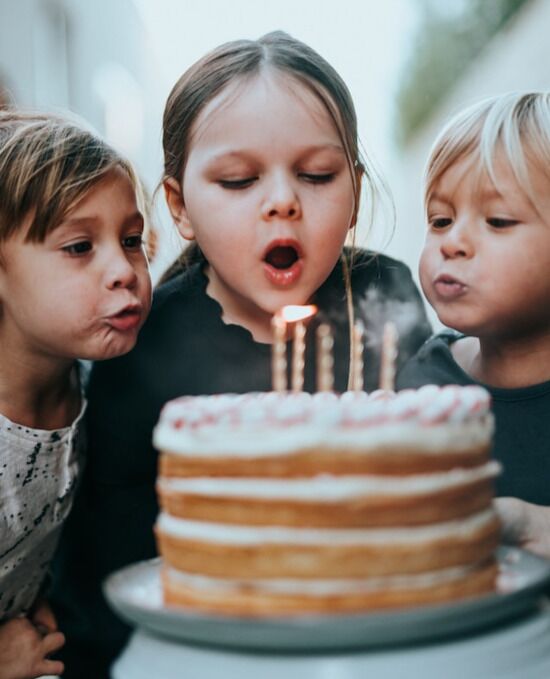 Children blowing out candles Three children blowing out candles at a birthday party
