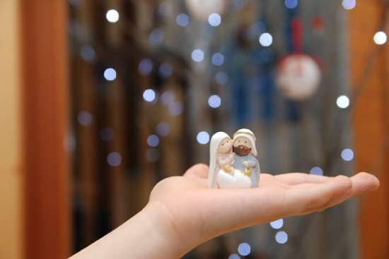 Nativity Figures Childs Hand A child holding small figurines of Mary, Joseph, and Jesus from a Christmas nativity scene