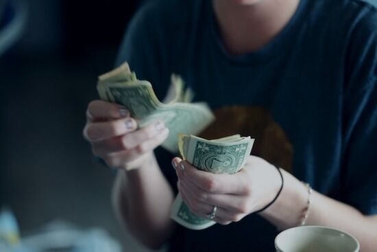 Counting money A young woman counting dollar bills to try to pay her debt