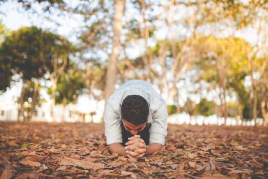 Man bowing in prayer on ground A man on his knees in worship of God