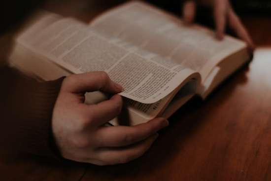 Open Bible A close-up of hands holding an open Bible. Thumb and index finger are prepared to flip the page to continue studying the Bible.