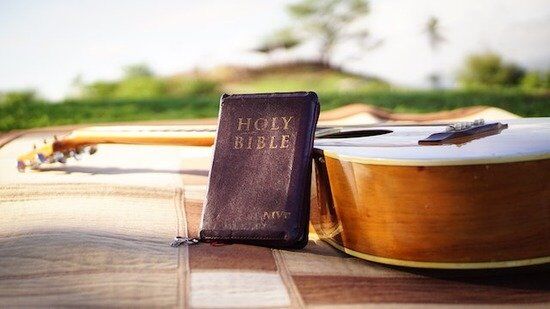 Bible and Guitar A Bible leaning against a guitar on a picnic blanket