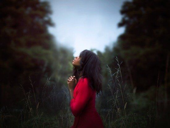Women Praying Outside A woman folding her hands and praying for the outpouring of the Holy Spirit, which is prophesied to happen in the last days