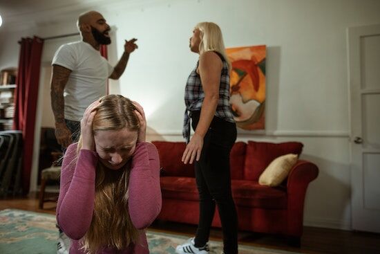 Couple Fighting A girl holding her hands over her ears while parents argue in the background