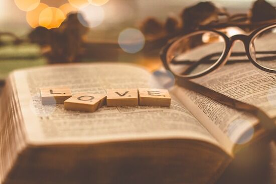 Love Word on Bible An open Bible with the scrabble letters spelling LOVE on top