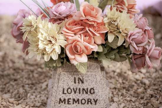 flowers on a tombstone Flowers on a tombstone with the words In Loving Memory engraved on it