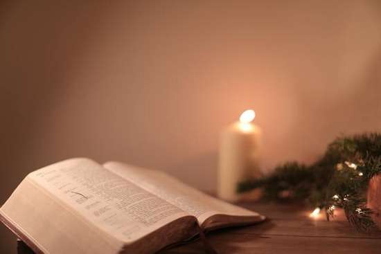 Bible at Christmas A Bible open with Christmas lights and candles surrounding it