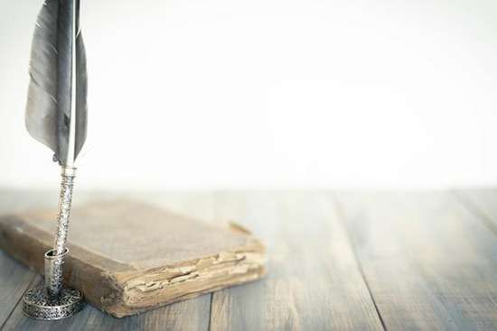 Feather Pen Old Book A worn Bible sits next to a feather quill.