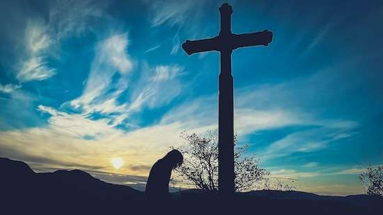 Person Kneeling at Cross A man kneeling in front of a cross