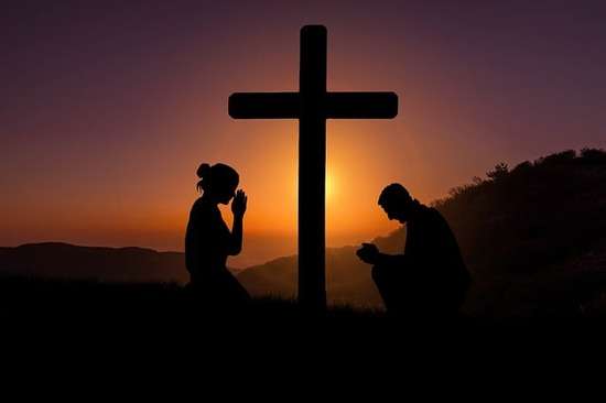 Man and Woman Kneeling at Cross A woman and man kneeling at the cross