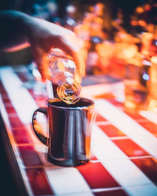 Blurry alcohol effect on mind A hand pouring alcohol into a mug. The image is blurry to represent the effect of alcohol on the mind.