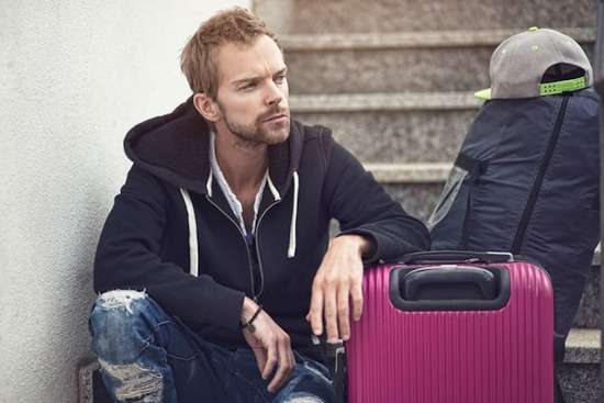 Man Sitting With Belongings after Divorce A man who's decided to divorce his wife sits by his suitcase on the stairs, preparing to move out of the house.