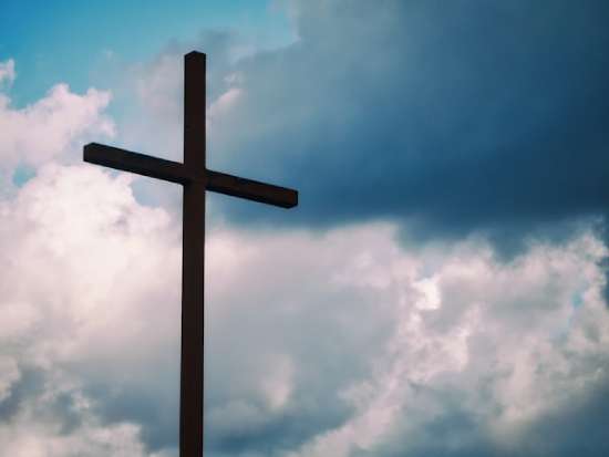 Cross The silhouette of a cross against a cloudy sky.