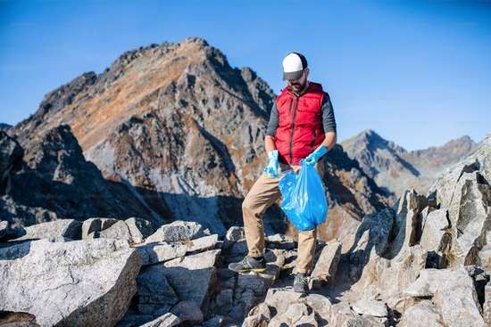 Man Picking-up Litter Stewardship A man with a bag, picking up garbage on a mountain trail