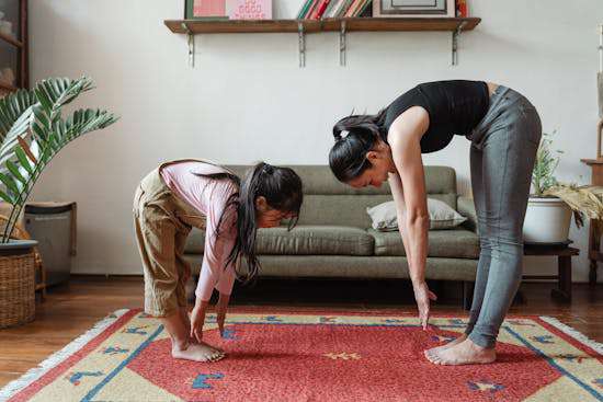 Mother and Daughter Exercising A woman and her daughter both stretching, reaching for their toes