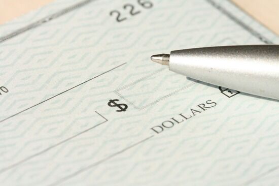 Pen Sitting on Top of a Cheque A visual of a blank check with a pen next to it indicates that on the surface, the Parable of the Talents talks about handling money.