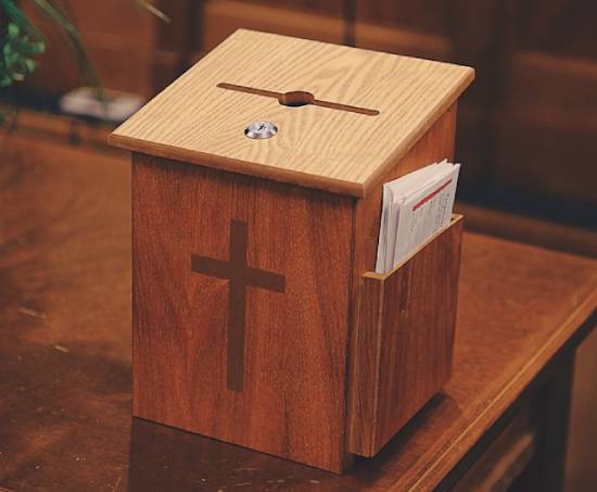 Wooden Tithe and Offering Box in a Church a small wooden box with a cross on the front and an open slit on the top, sitting on a wooden desk
