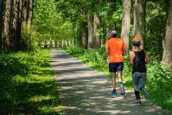A man and Woman Running Together in the morning A man and woman running on a trail in a forest. Exercising outdoors can do wonders for our health!