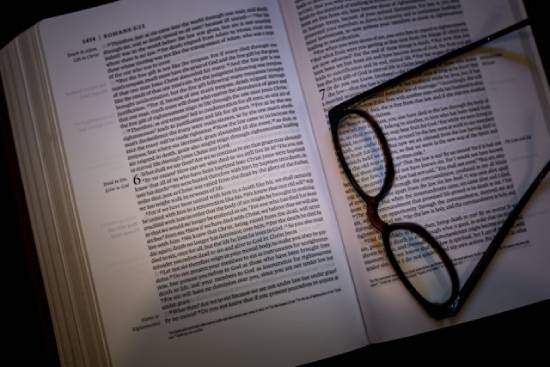 Bible open to Romans 6 A pair of glasses rests on a Bible open to Romans 6, an important passage regarding salvation.