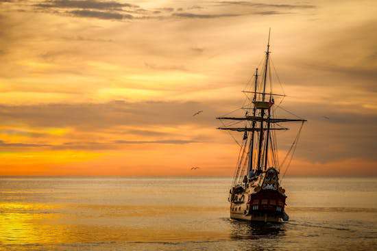 Ship Sailing on the Water A wooden ship sailing into a sunset