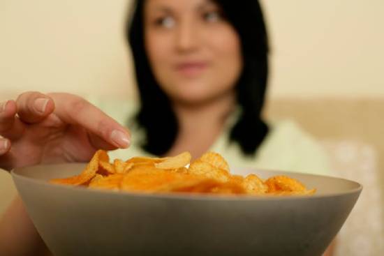 A woman reaches for a bowl of chips, representing the human struggle with the spiritual fruit of self control.