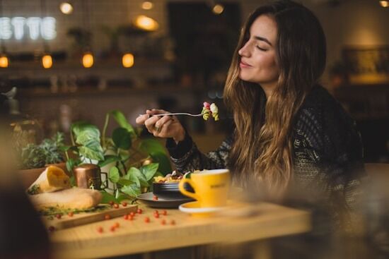 Woman Holding Fork Ready to Eat A woman smiles as she prepares to take a bite of her vegetarian pasta salad.