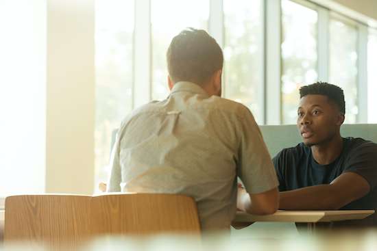 Two seated at a table, in deep discussion