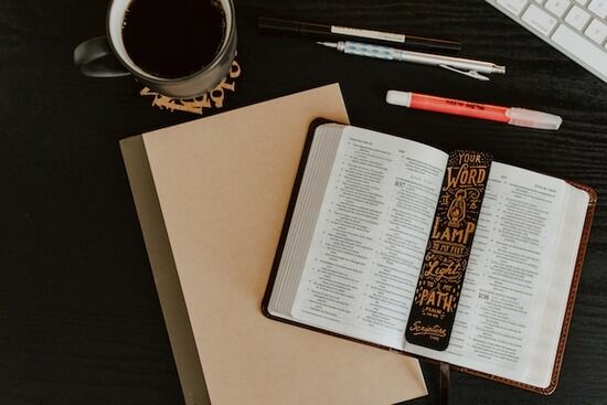 Bible Study Materials An open Bible on a desk full of Bible study materials