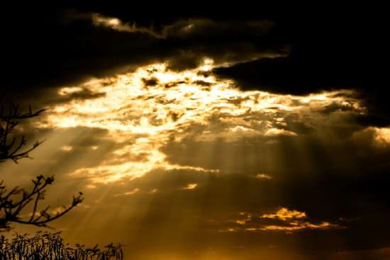 Gold sunbeams shine through dark clouds, illustrating what the Second Coming could look like.