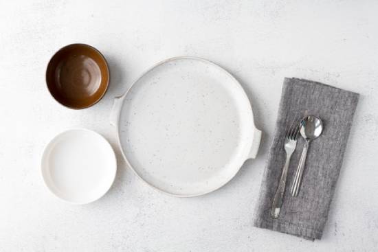 Empty plates and bowls alongside silverware, symbolizing the choice to abstain from food.