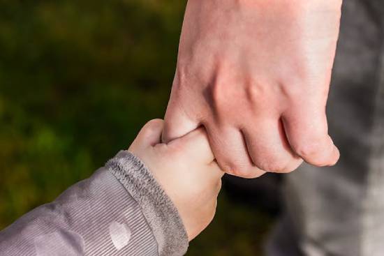 A child wrapping their small hand around their parent's finger.